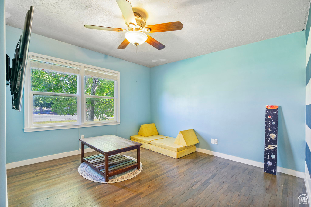 Sitting room with dark wood-type flooring, ceiling fan, and a textured ceiling