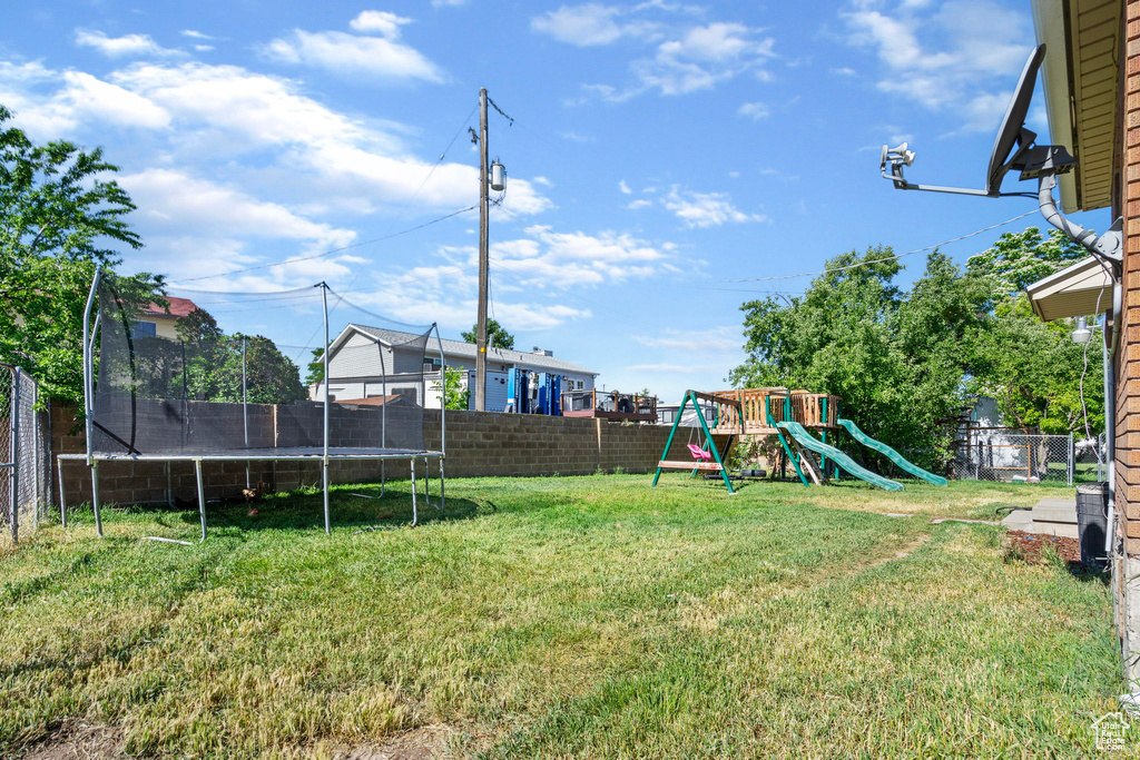 View of yard with a playground and a trampoline