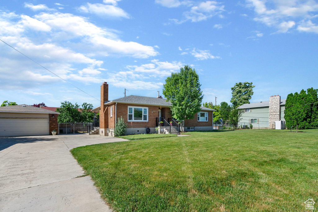 Single story home featuring a front yard, an outdoor structure, and a garage