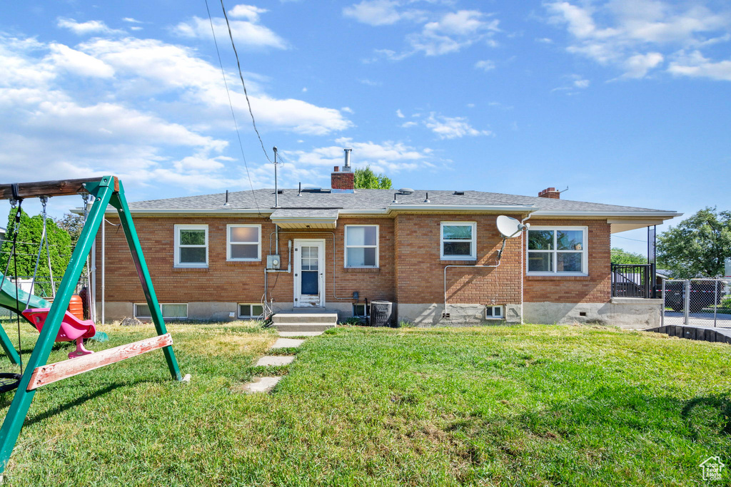 Rear view of house featuring a playground and a yard