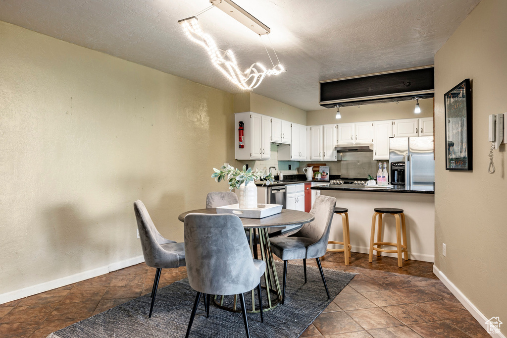 Dining area with an inviting chandelier, sink, dark tile flooring, and rail lighting