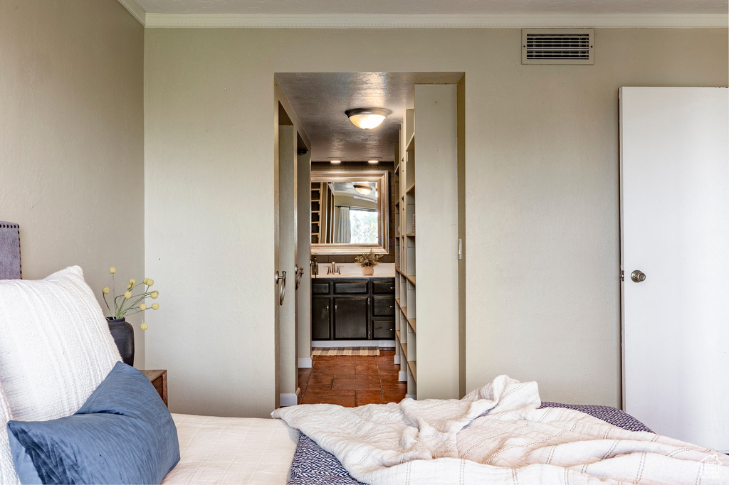 Tiled bedroom featuring sink, crown molding, and ensuite bath