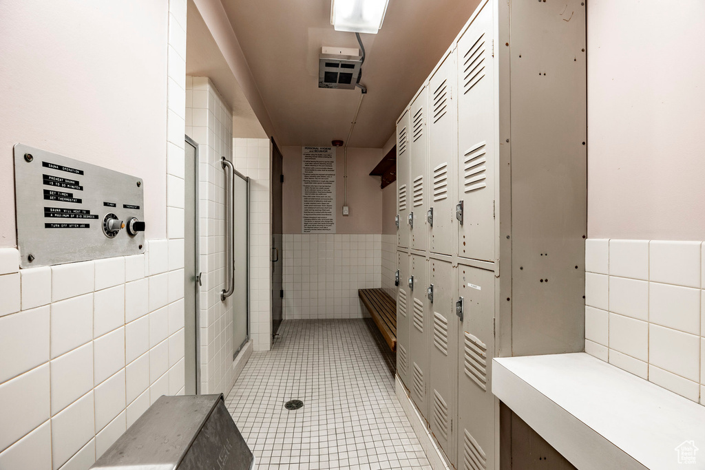 Bathroom with tile walls, an enclosed shower, and tile flooring