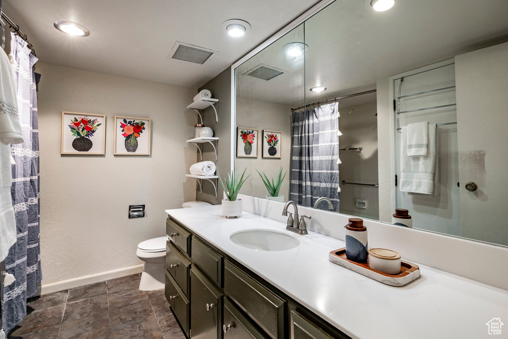 Bathroom with vanity with extensive cabinet space, toilet, and tile floors