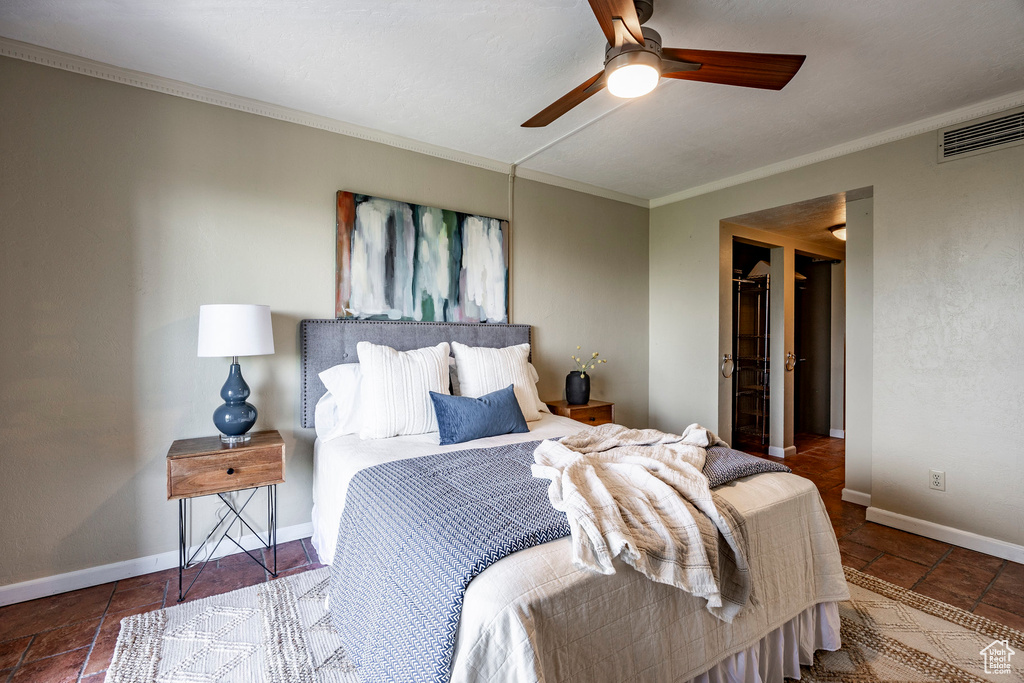 Bedroom with tile floors, a walk in closet, crown molding, and ceiling fan