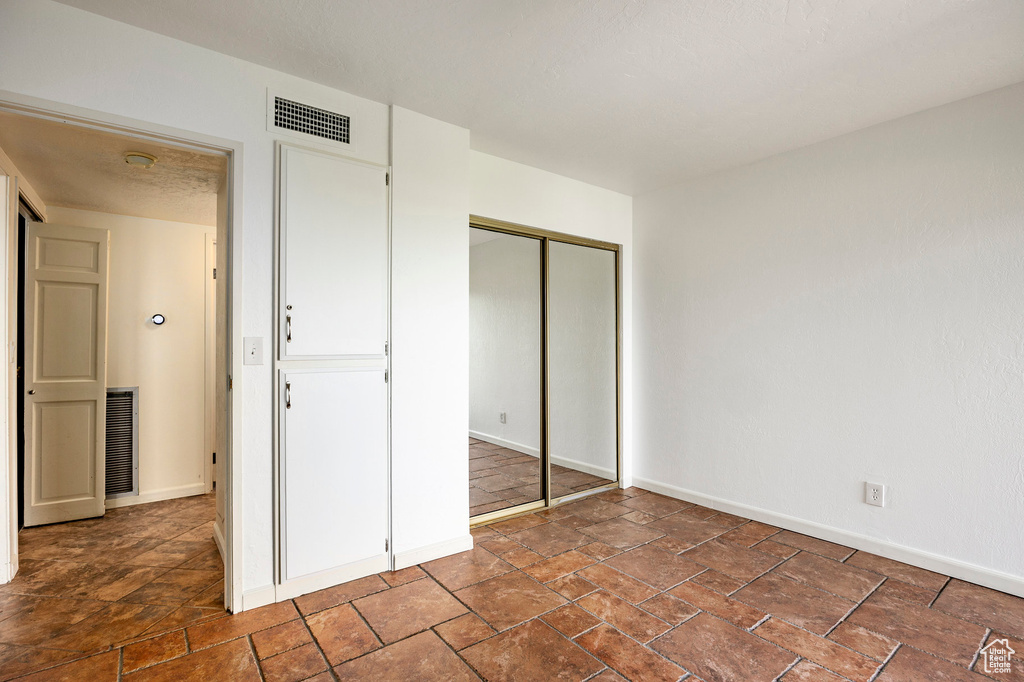 Unfurnished bedroom with a closet and dark tile floors