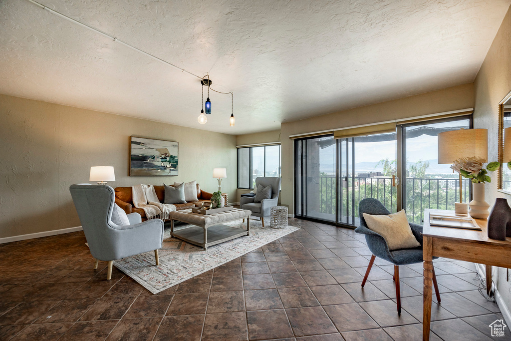 Living room featuring a wealth of natural light, dark tile flooring, and a textured ceiling