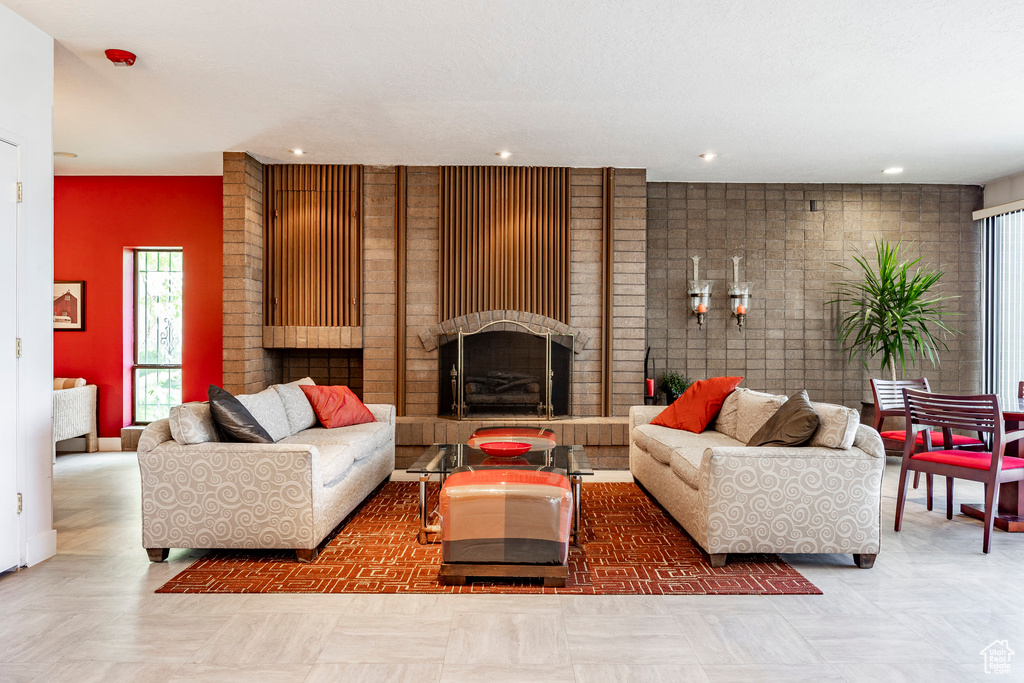 Living room with tile floors, brick wall, and a brick fireplace