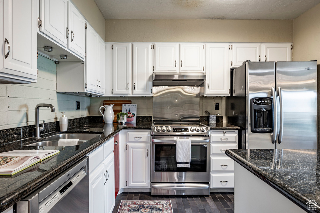 Kitchen with sink, white cabinets, backsplash, and appliances with stainless steel finishes