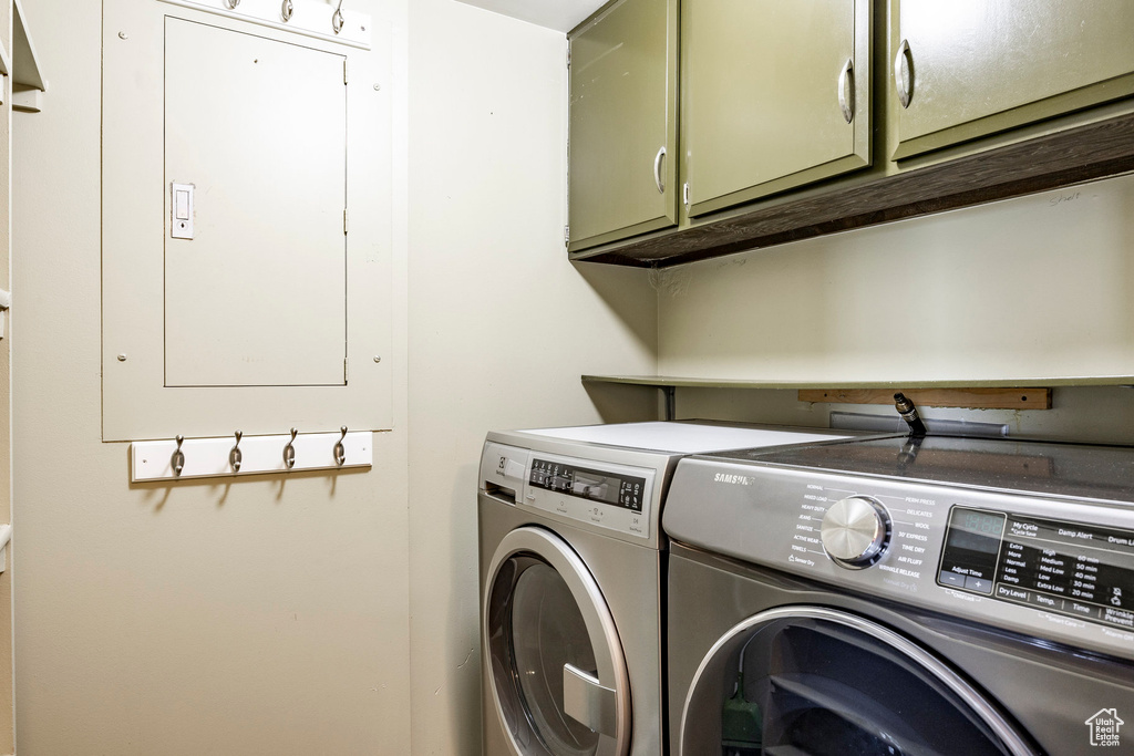 Clothes washing area featuring washer and dryer and cabinets