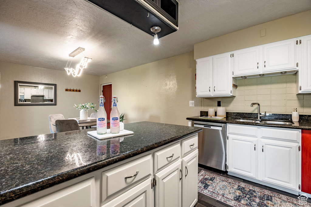 Kitchen with dishwasher, dark stone countertops, backsplash, sink, and white cabinets