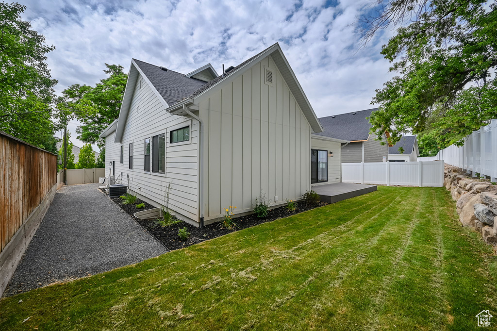 View of side of property with central AC and a yard