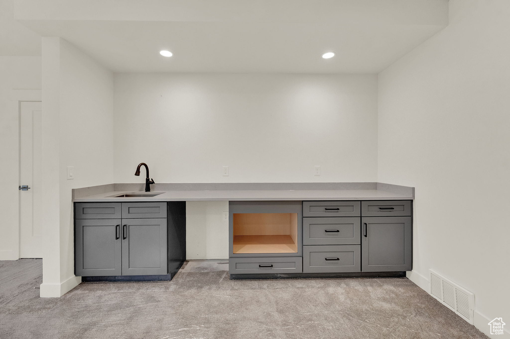 Bar featuring sink, gray cabinetry, and light colored carpet