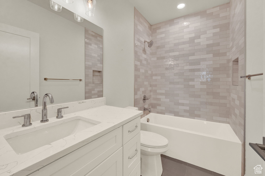 Full bathroom featuring tile flooring, oversized vanity, toilet, and tiled shower / bath combo