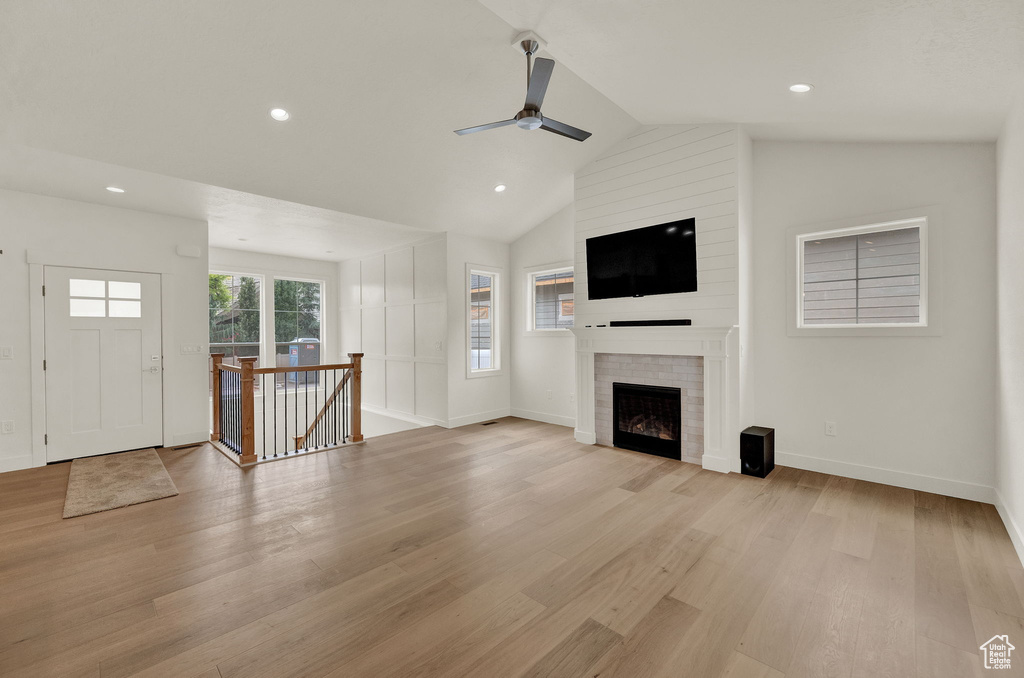 Unfurnished living room featuring ceiling fan, light hardwood / wood-style floors, a fireplace, and lofted ceiling