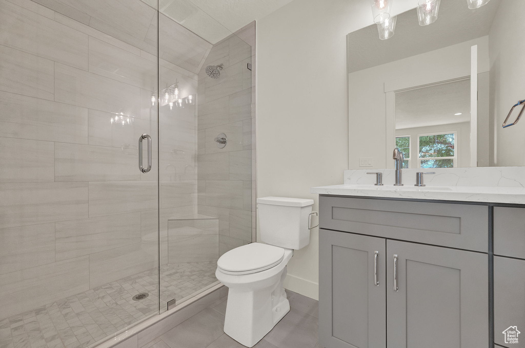 Bathroom featuring tile floors, an enclosed shower, large vanity, and toilet