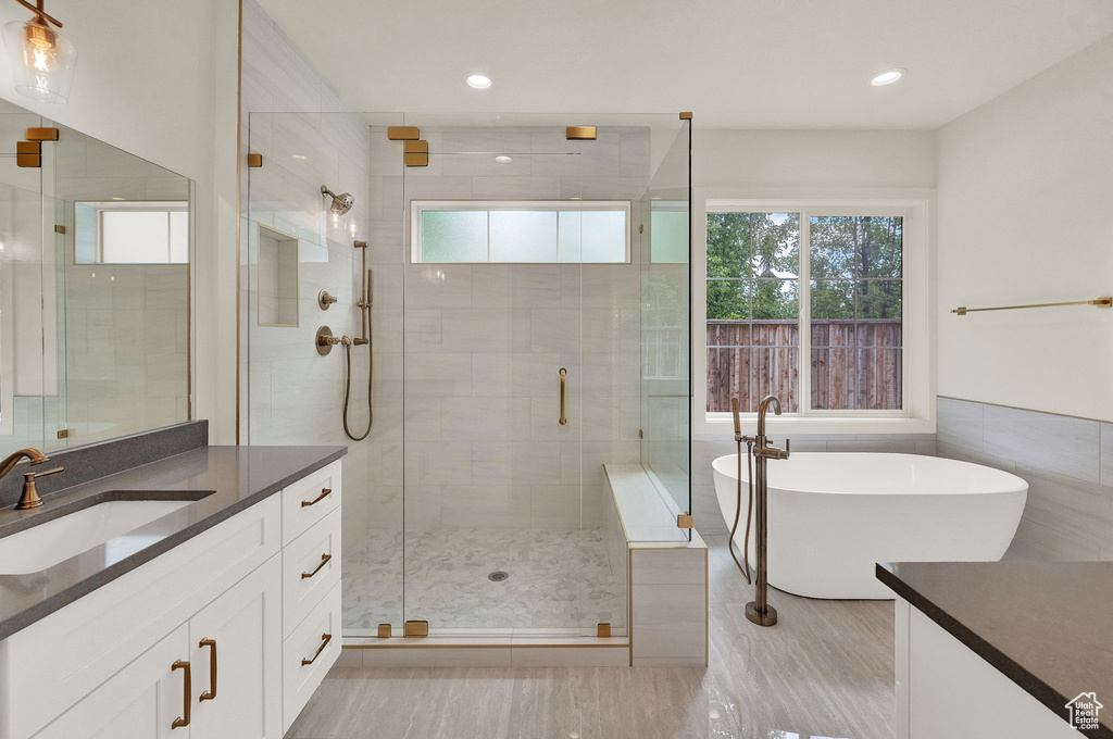 Bathroom featuring plus walk in shower, tile flooring, tile walls, and vanity