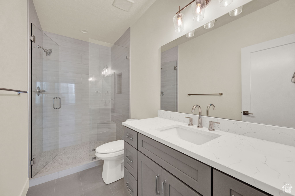 Bathroom featuring tile flooring, an enclosed shower, toilet, and large vanity