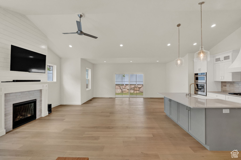 Kitchen with stainless steel appliances, white cabinetry, light hardwood / wood-style floors, and lofted ceiling