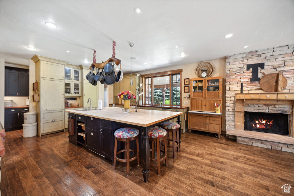 Kitchen with a center island with sink, dark hardwood / wood-style flooring, a breakfast bar, and butcher block countertops