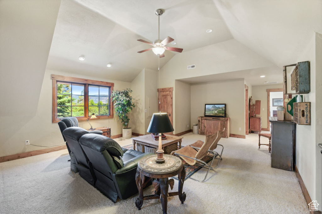 Carpeted living room with ceiling fan and vaulted ceiling