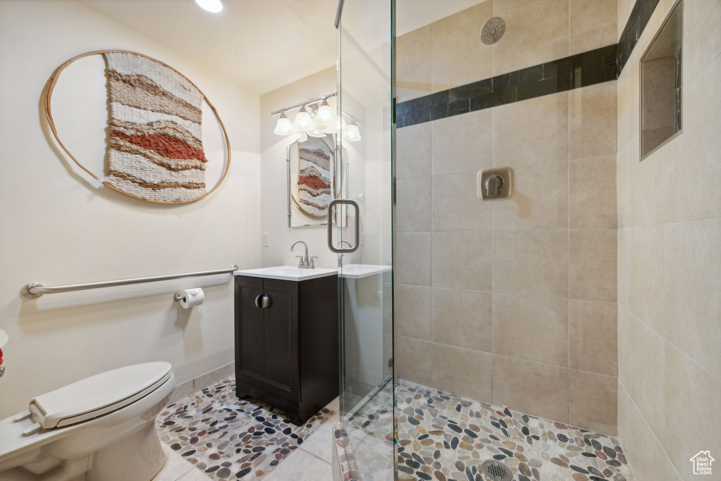 Bathroom with tiled shower, tile floors, large vanity, and toilet