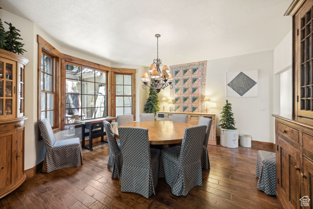 Dining space with dark wood-type flooring and a chandelier