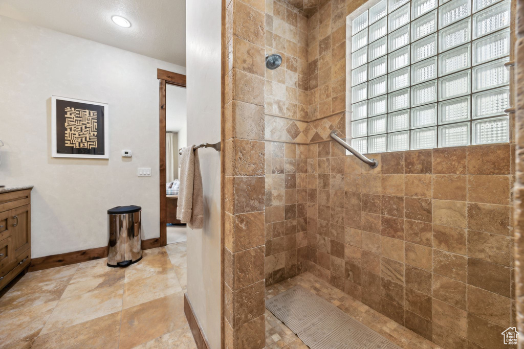 Bathroom featuring tile floors, tiled shower, and vanity