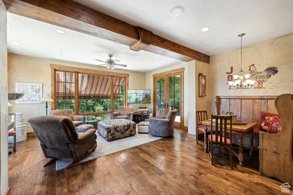 Living room with hardwood / wood-style floors, beam ceiling, french doors, and ceiling fan with notable chandelier