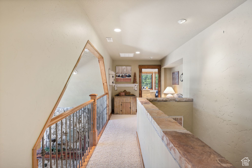 Hallway featuring light colored carpet