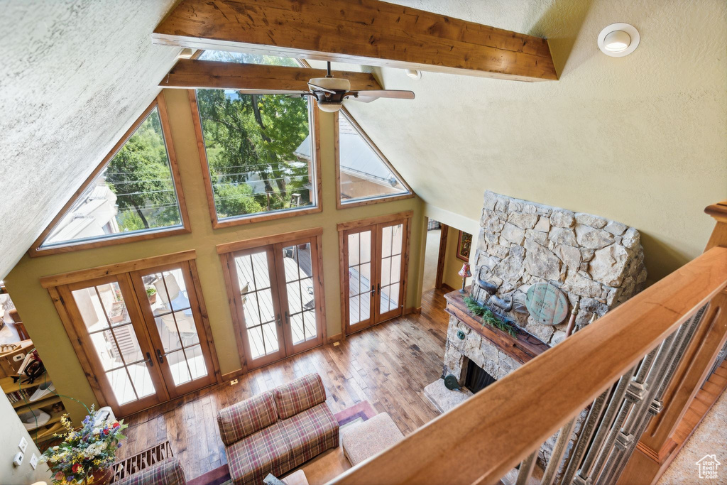 Living room with a fireplace, ceiling fan, hardwood / wood-style flooring, beamed ceiling, and french doors