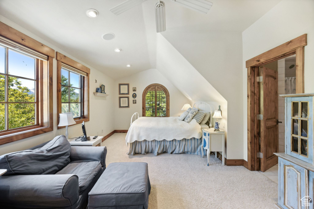 Bedroom featuring lofted ceiling, multiple windows, and light colored carpet