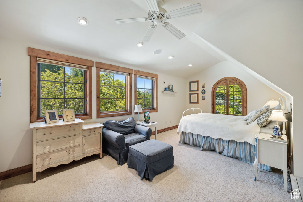 Carpeted bedroom with ceiling fan, multiple windows, and vaulted ceiling