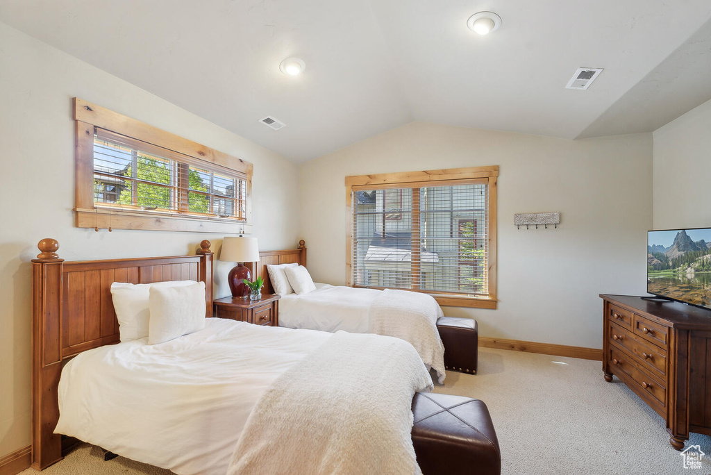 Bedroom with light carpet and lofted ceiling