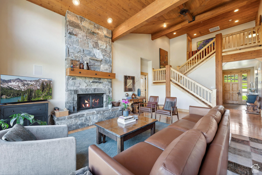 Living room featuring a towering ceiling, a fireplace, hardwood / wood-style floors, wood ceiling, and beamed ceiling