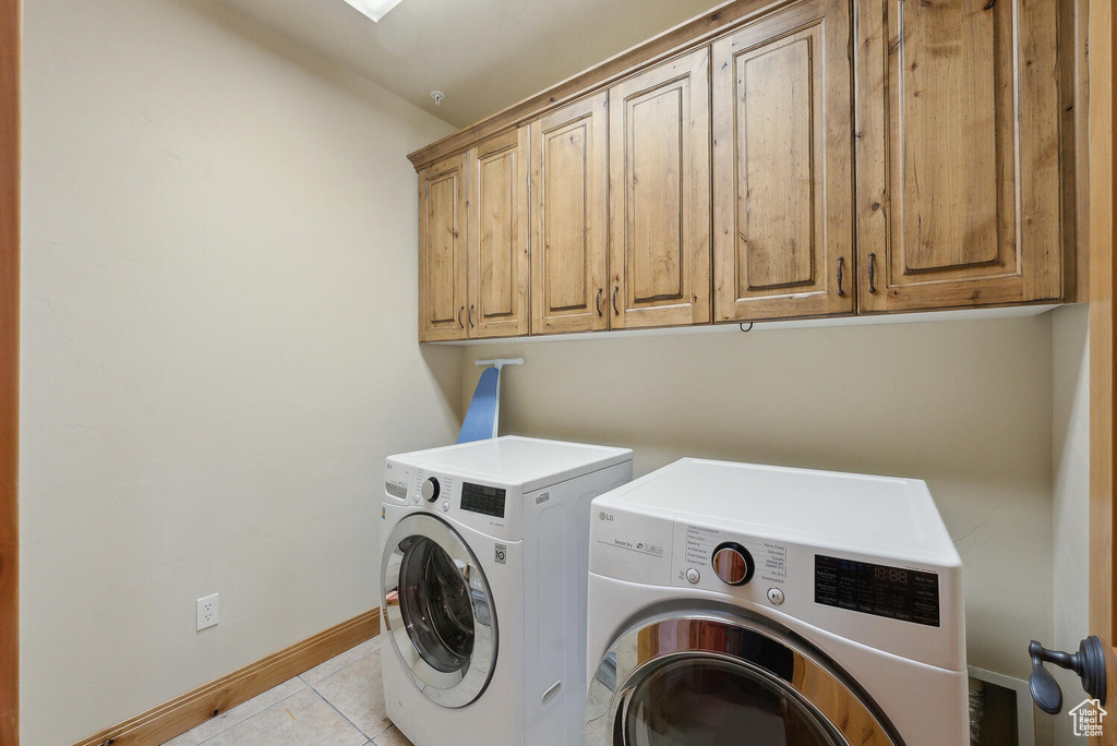 Laundry area with cabinets, light tile flooring, and washing machine and clothes dryer