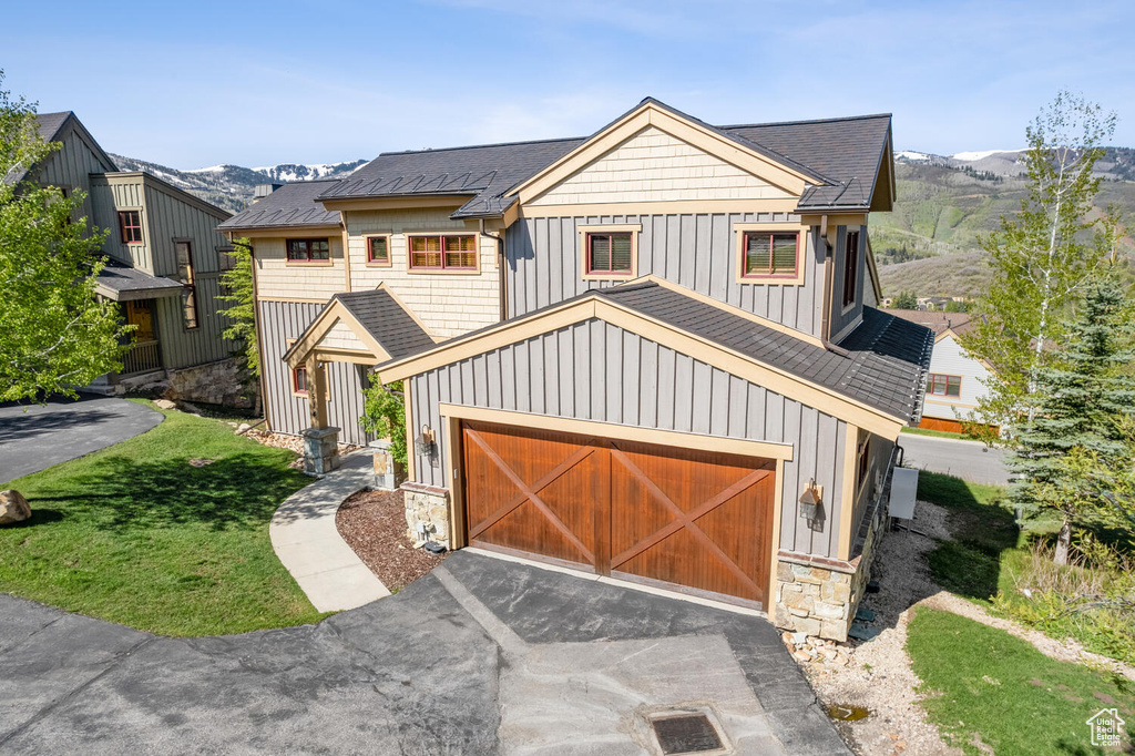 View of front of property featuring a garage, a front yard, and a mountain view