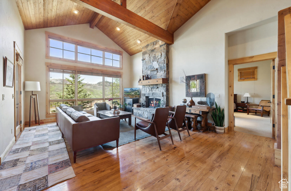 Living room featuring high vaulted ceiling, beam ceiling, light hardwood / wood-style floors, and a fireplace