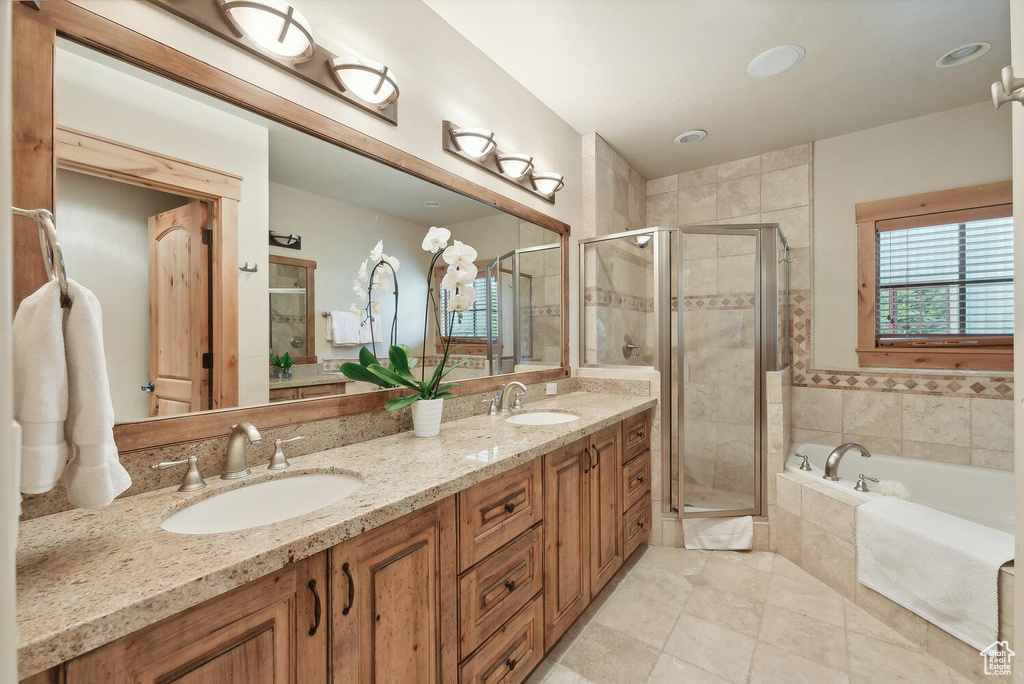 Bathroom with tile flooring, independent shower and bath, large vanity, and double sink