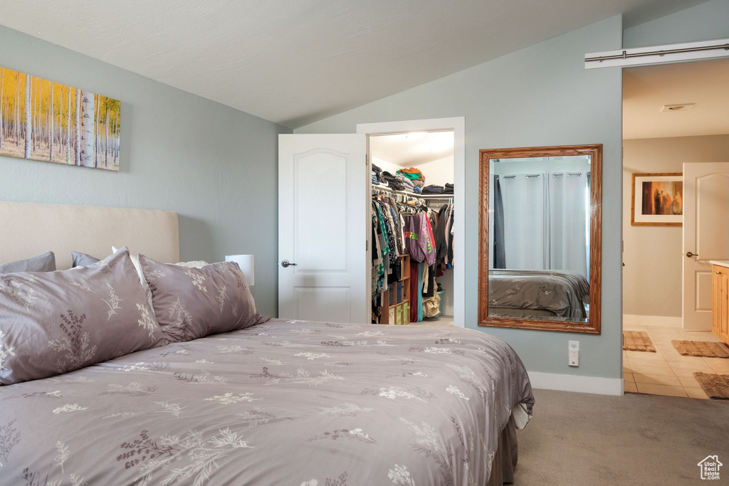 Bedroom featuring lofted ceiling, a closet, a walk in closet, and carpet flooring