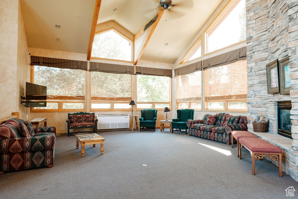 Interior space with high vaulted ceiling, ceiling fan, and a stone fireplace