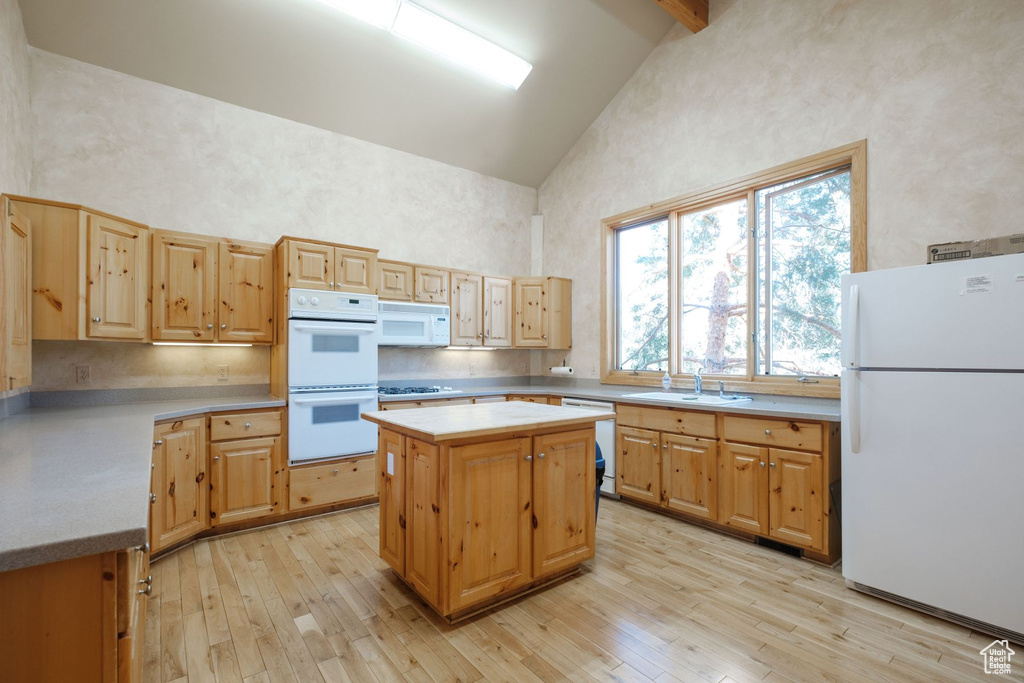 Kitchen with light hardwood / wood-style floors, white appliances, a kitchen island, high vaulted ceiling, and sink