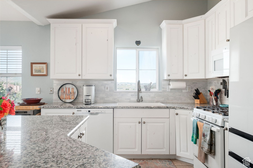 Kitchen featuring vaulted ceiling, tasteful backsplash, white cabinets, sink, and white appliances