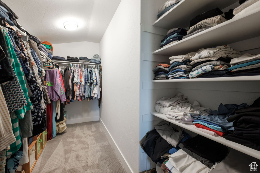 Spacious closet featuring vaulted ceiling and carpet floors