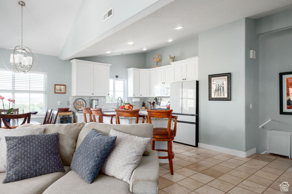 Living room with an inviting chandelier, lofted ceiling, and light tile floors