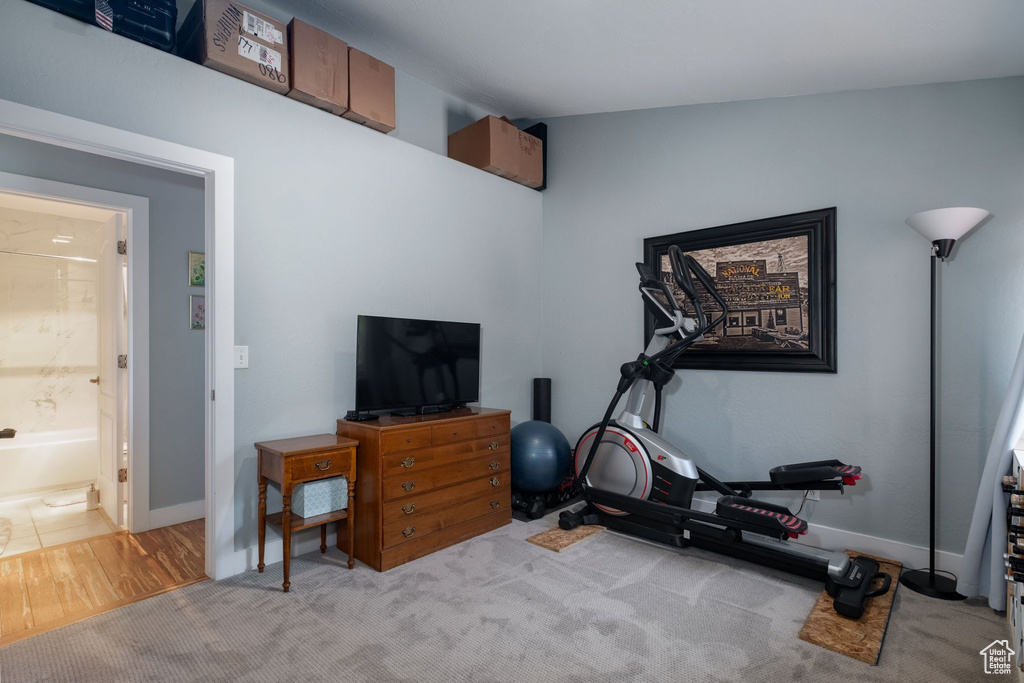 Exercise room featuring lofted ceiling and light carpet