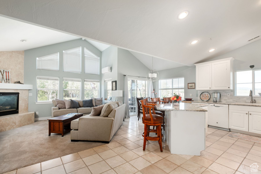 Kitchen with a healthy amount of sunlight, white cabinetry, white dishwasher, and a premium fireplace