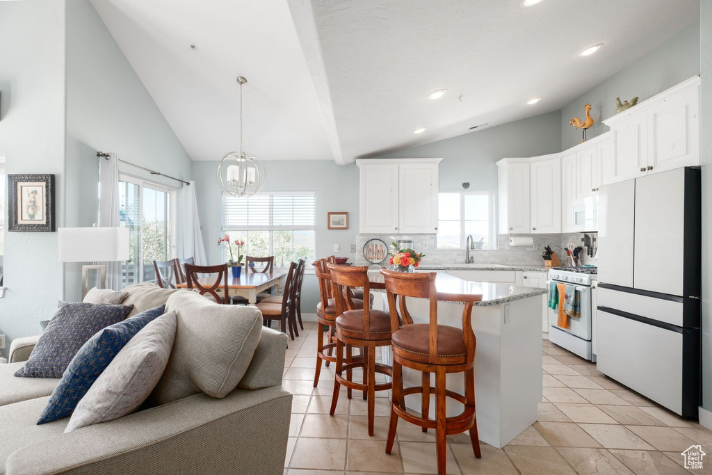 Kitchen with a healthy amount of sunlight, white appliances, light tile flooring, and tasteful backsplash