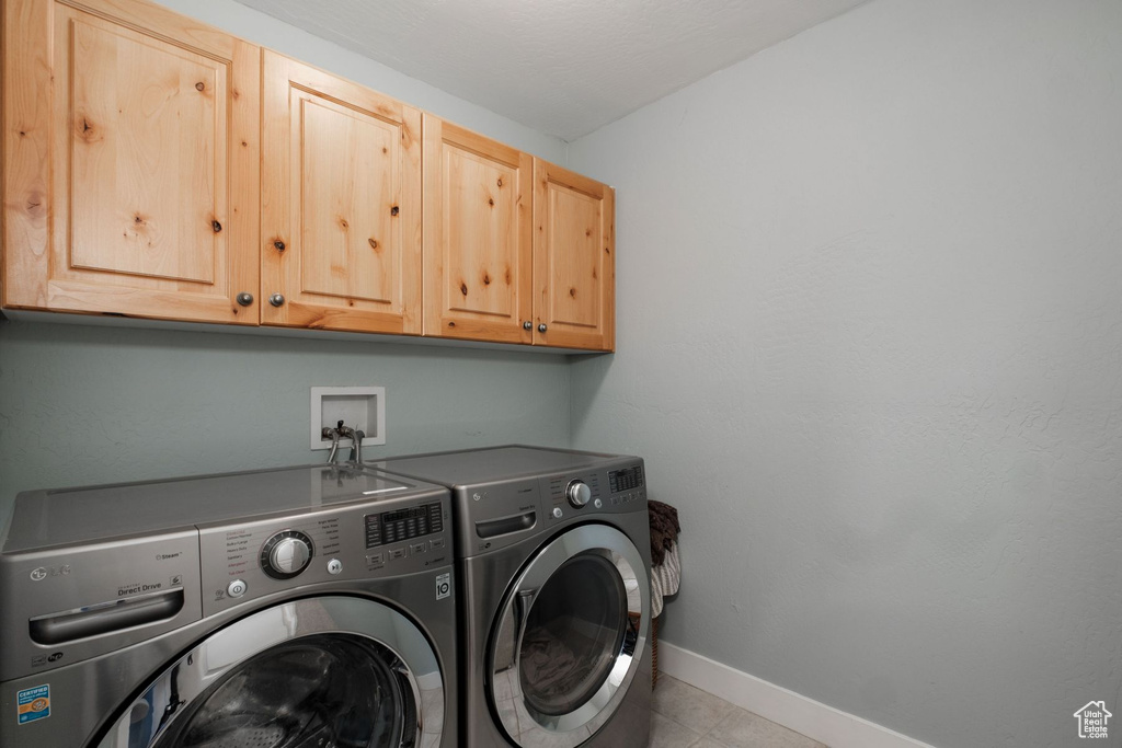 Laundry area featuring washing machine and dryer, washer hookup, light tile flooring, and cabinets