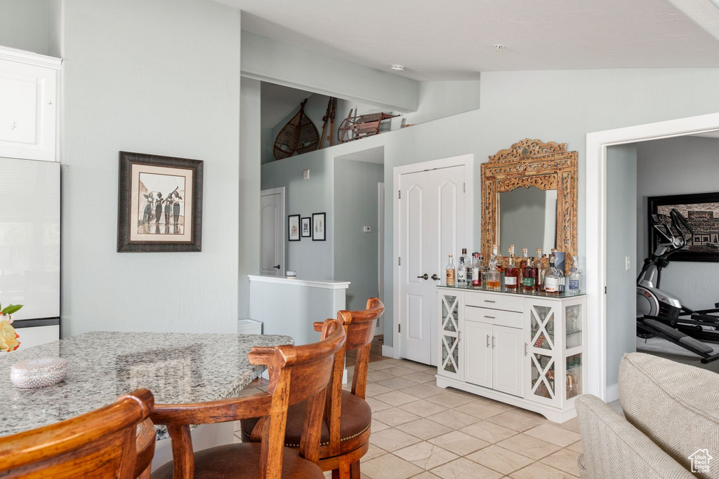 Dining area featuring vaulted ceiling and light tile floors